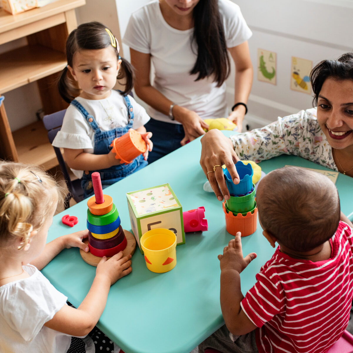 Nursery children playing with teacher in the classroom